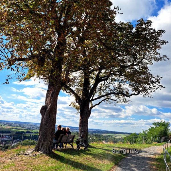 Herbst, Bank mit 3 Personen, die in die Landschaft schauen